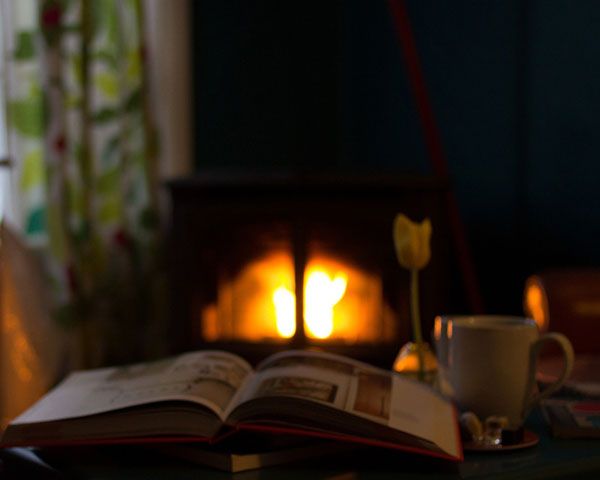 fireside scene with an open book and a mug of tea by firelight