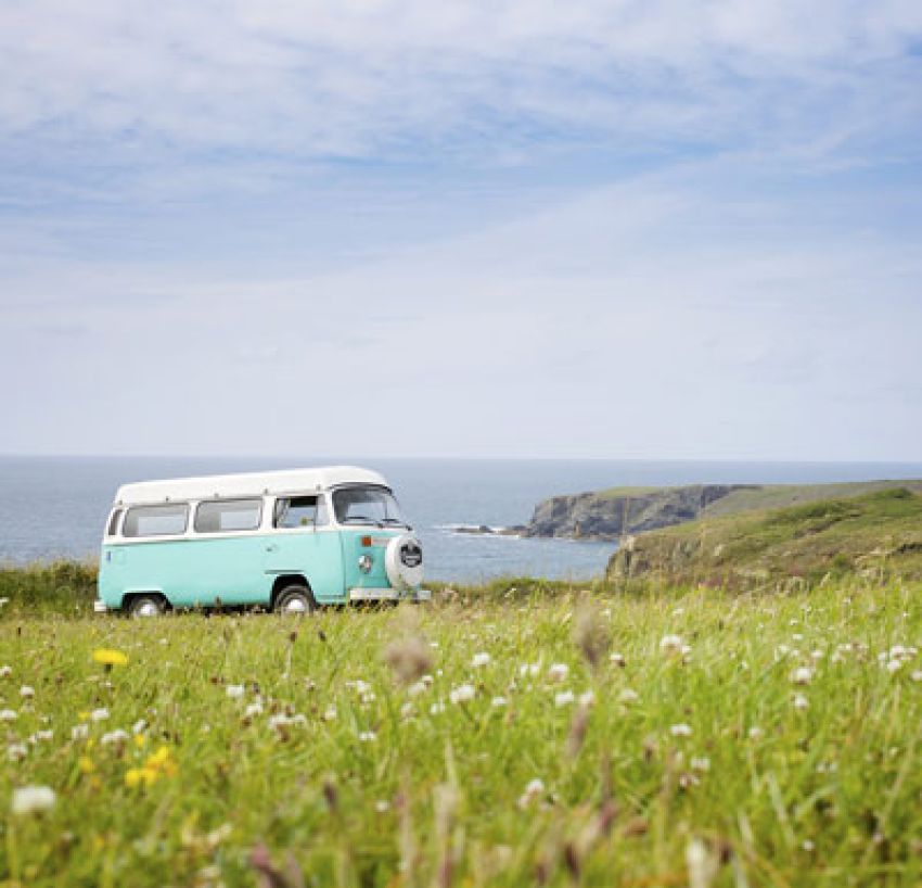 vintage campervan parked at coast with wild grass in foreground