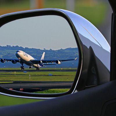 plane taking off reflected in the side mirror of a car