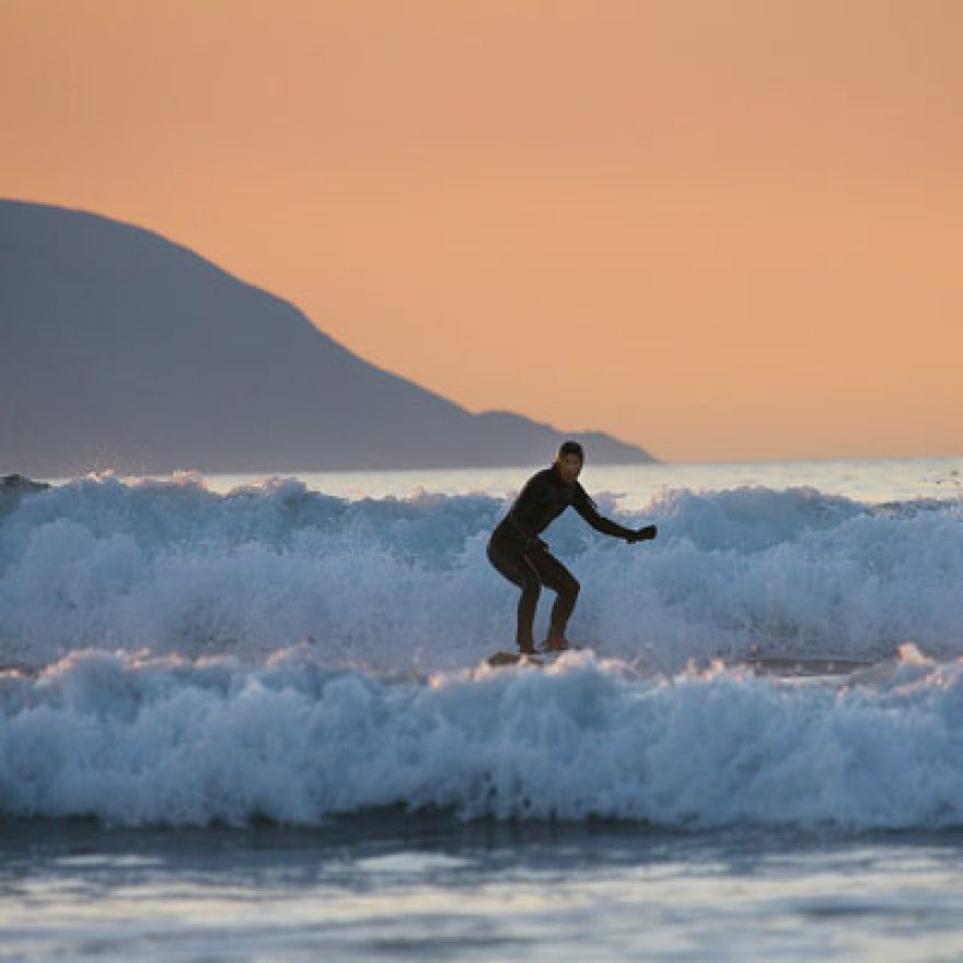 a single surfer surfing in evening light at Brandon Bay Dingle Peninsula Ireland
