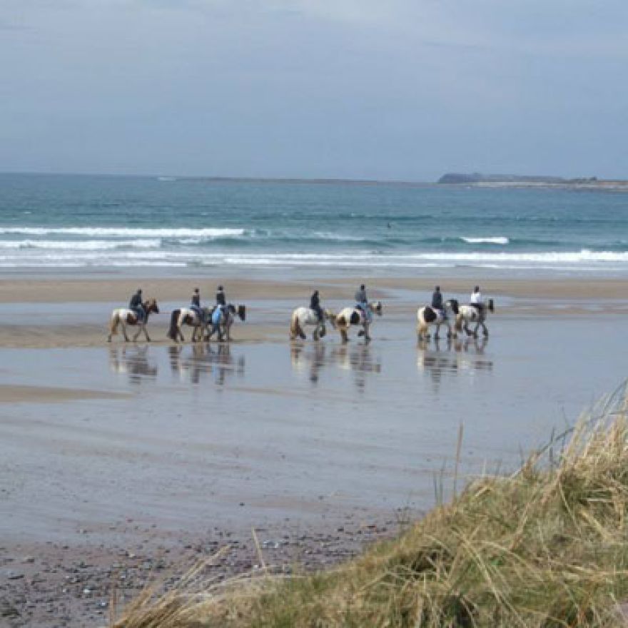 seven horses and riders on Ventry beach with sea behind them dingle peninsula ireland