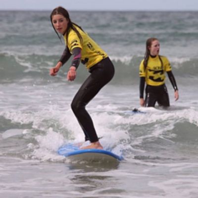 two young girls learning to surf with one standing on a surf board Dingle Peninsula