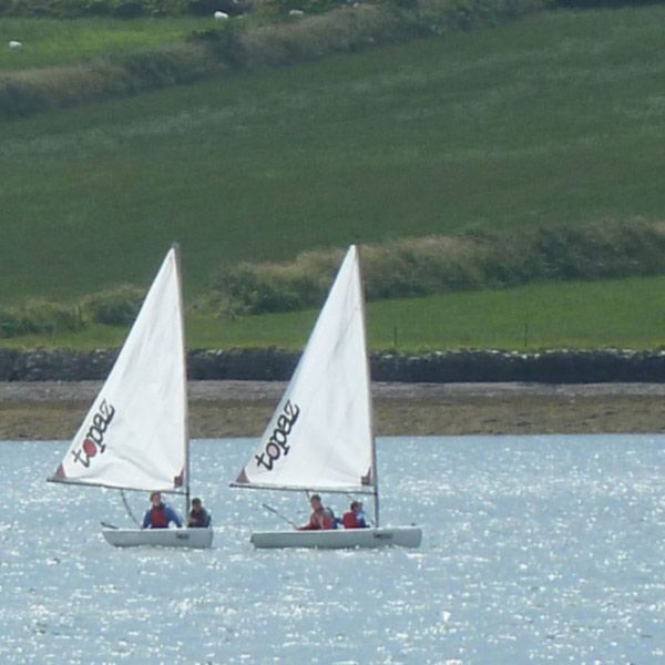 two small boats sailing in dingle harbour with 2 people in each boat