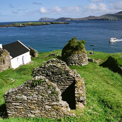abandoned village on blasket island with boat and mainland in background  