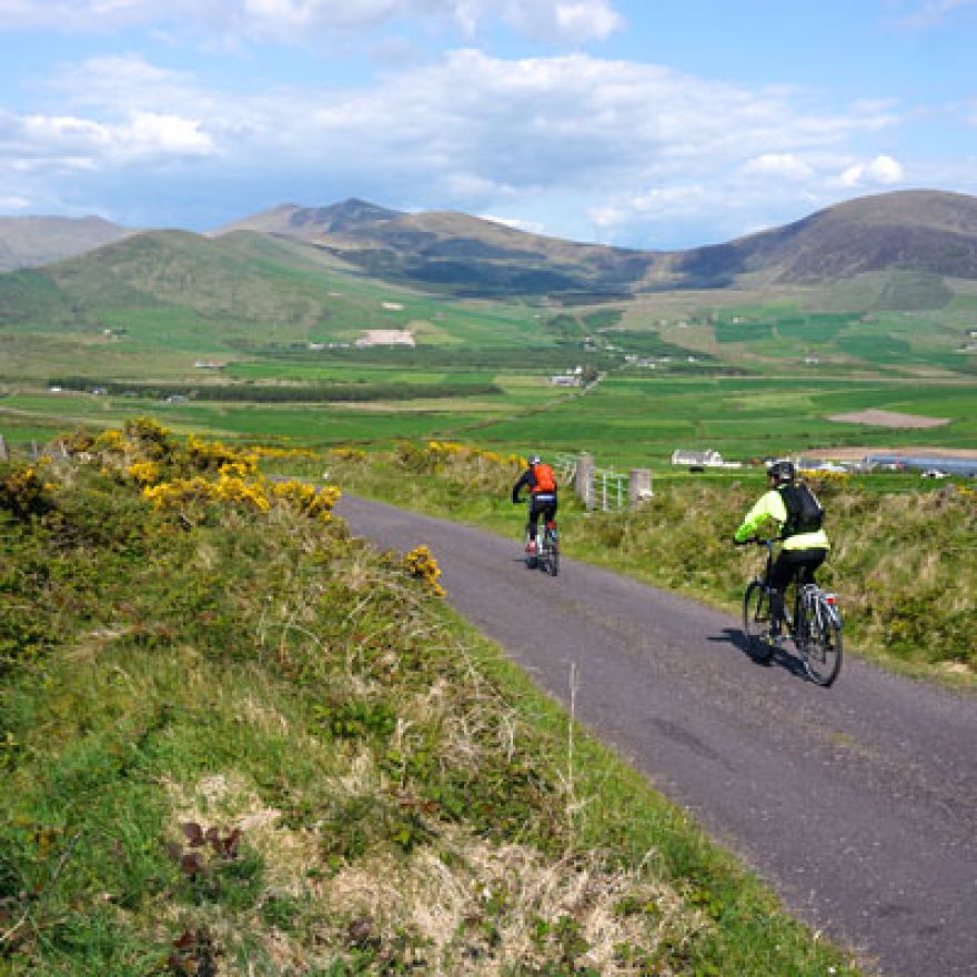 two cyclists on country road with mountains behind dingle peninsula ireland